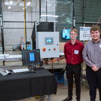 Two students posing in front of their project